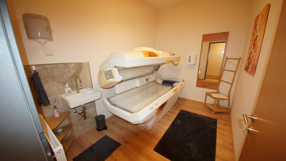 A room featuring a tanning bed, sink, and mirror. | © Der Marienhof