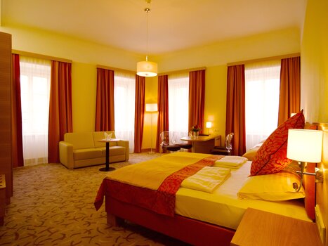 A bright hotel room with a double bed and seating areas. | © Hotel Drei Raben