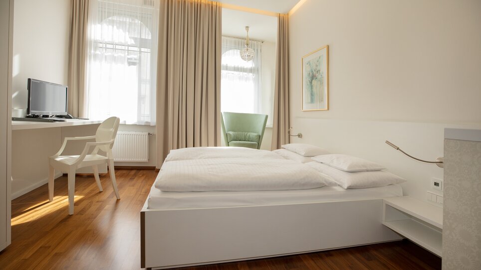 Ein helles Schlafzimmer mit Bett, Schreibtisch und Stuhl. | © Gollner