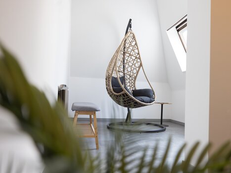 Rattan hanging chair in a bright room. | © Hotel Gollner