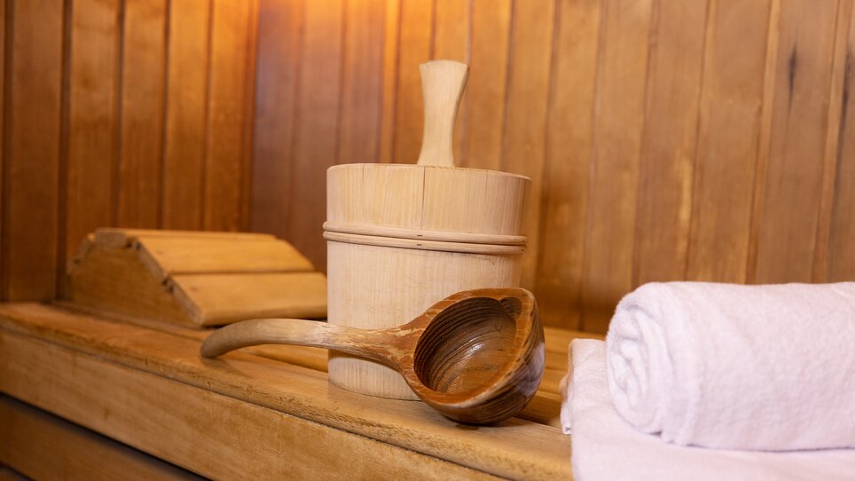 Holzschöpflöffel und Sauna-Eimer auf einer Holzbank. | © Hotel Gollner