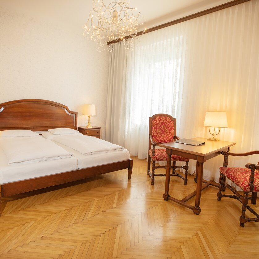 Una camera da letto con letto matrimoniale, mobili in legno e tavolo con sedie. | © Gollner