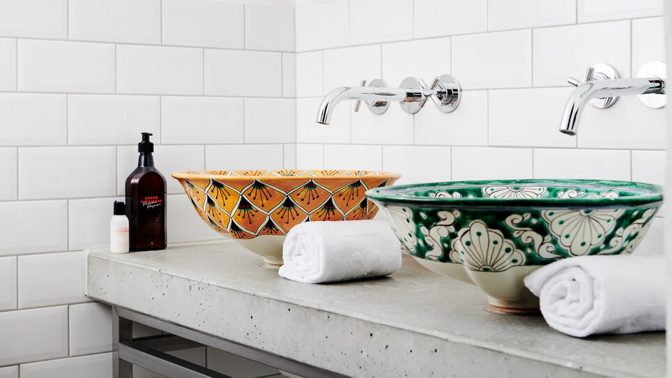 Zwei bunte Waschbecken, Handtücher und Pflegeprodukte auf einem Tisch. | © Grand Hotel Wiesler