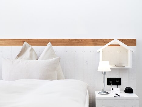 Un letto con cuscini, lampada da comodino e decorazioni.