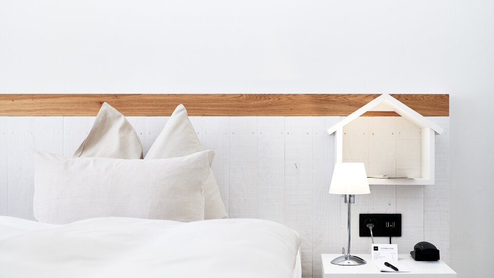 Ein Bett mit Kissen, Nachttischleuchte und Dekoration.