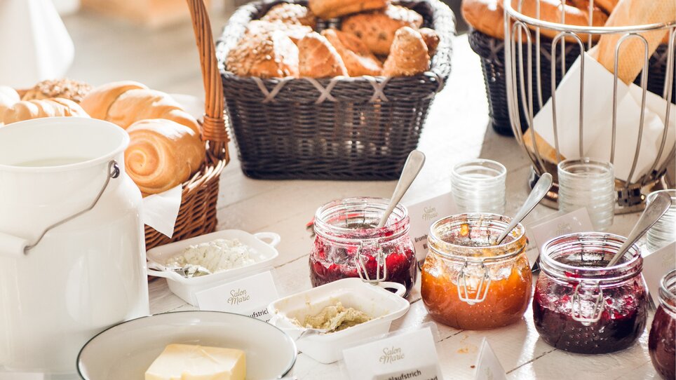 Ein Tisch mit frischen Brötchen, Marmelade und Butter.
