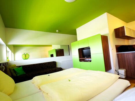 Una stanza con soffitto verde, divano nero e cucina. | © Hotel Greenrooms