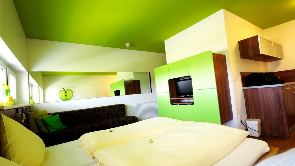 Una stanza con soffitto verde, divano nero e cucina. | © Hotel Greenrooms