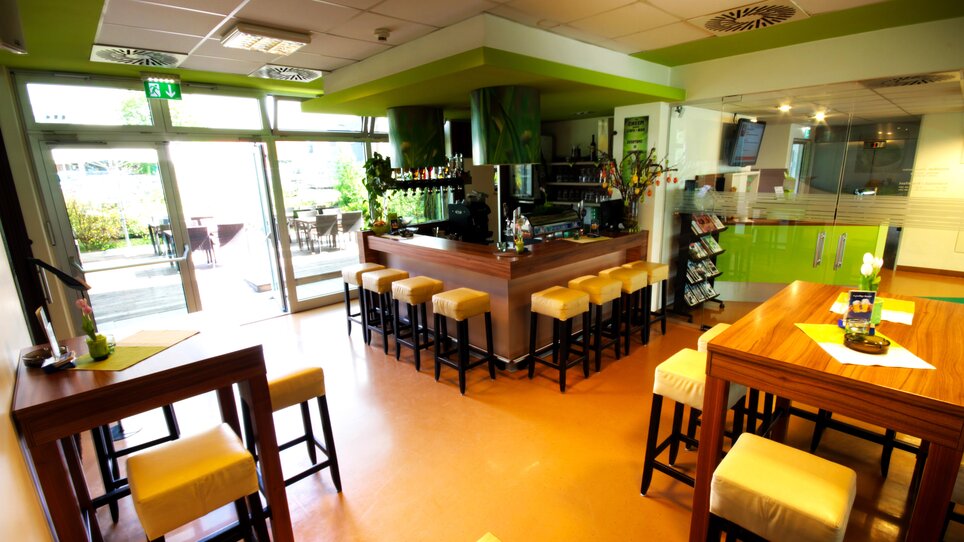 Vista del bar e posti a sedere con decorazioni verdi.