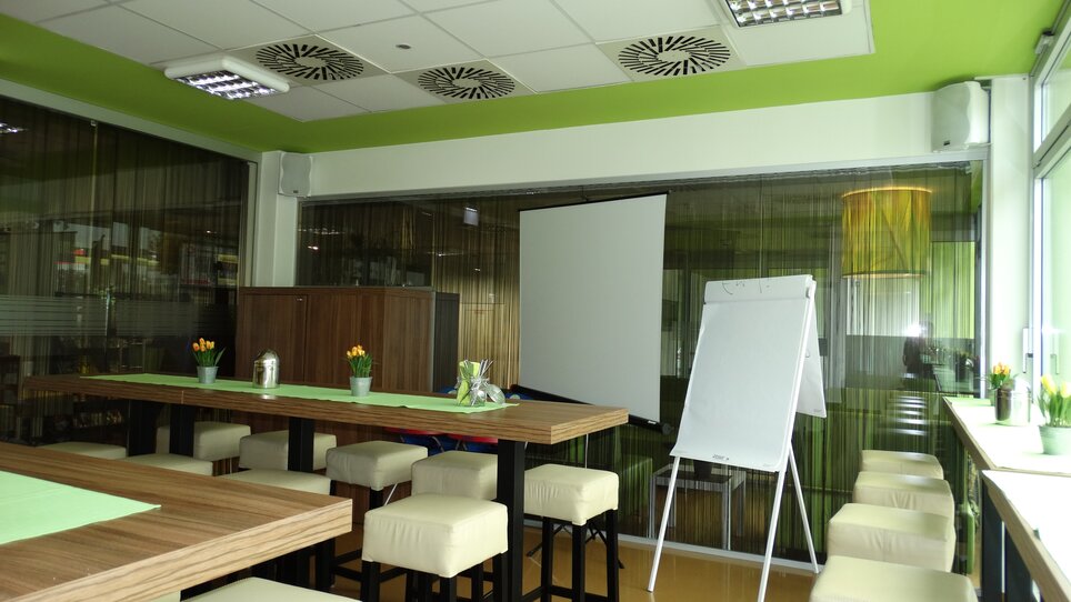 Una sala riunioni con tavoli, sedie, un flipchart e un proiettore.