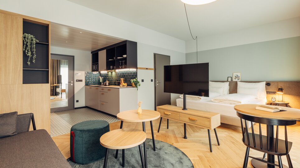 Camera moderna con cucina, TV e area notte in harry's home Graz-Smart City. | © harry's home Graz-Smart City - Daniel Zangerl