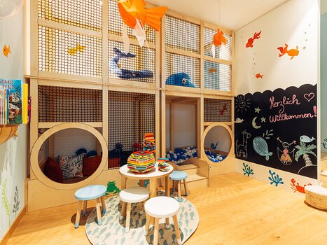 Area gioco colorata per bambini con scaffali di libri e tavoli in harry's home Graz-Smart City. | © harry's home Graz-Smart City - Daniel Zangerl