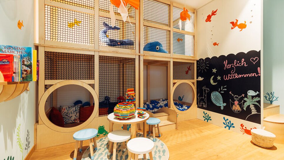 Area gioco colorata per bambini con scaffali di libri e tavoli in harry's home Graz-Smart City. | © harry's home Graz-Smart City - Daniel Zangerl