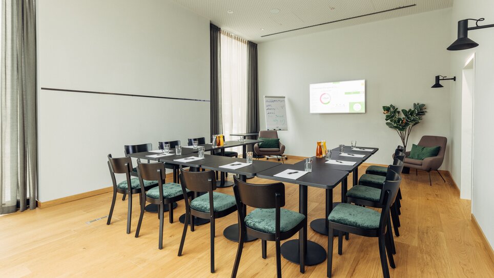 Ein Konferenzraum mit Tischen, Stühlen und einem Bildschirm im harry's home Graz-Smart City. | © harry’s home hotels - Daniel Zangerl