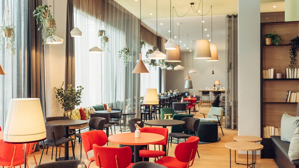 Un'elegante area lounge con sedie e piante colorate, fonti luminose e un design aperto. | © Harrys Home Graz Smart City - Daniel Zangerl