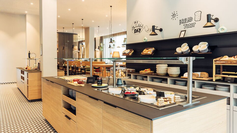 L'area colazione con una varietà di cibi e un'atmosfera moderna. | © Harrys Home Graz Smart City - Daniel Zangerl