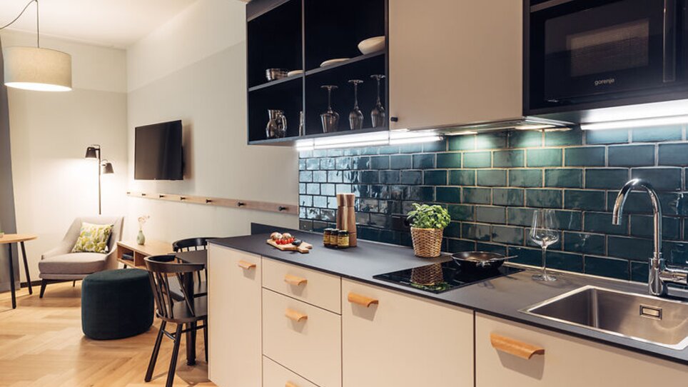 Cucina moderna adiacente ad area living con piastrelle verdi. | © Harrys Home Graz Smart City - Daniel Zangerl