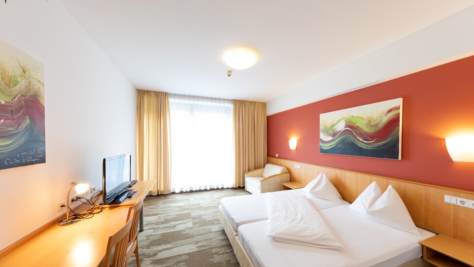 A bright double room with large windows and modern furniture. | © Harry Schiffer