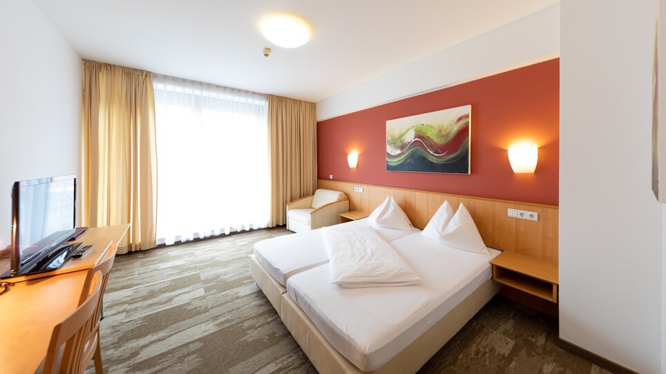 Bright double room with two beds and a television. | © Harry Schiffer