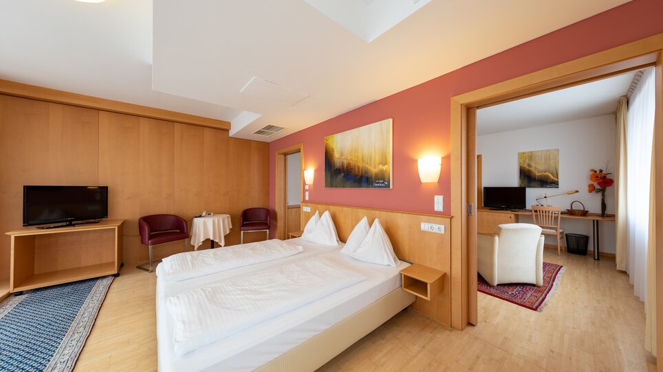 Modern double room with two beds, TV and seating area. | © Harry Schiffer