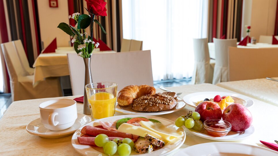 A breakfast table with croissants, fruits, cheese, cold cuts, and drinks. | © Harry Schiffer