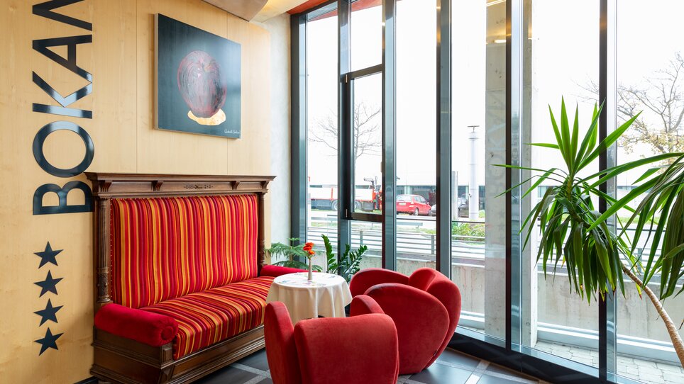 Modern seating area in Hotel Bokan with red sofa and artwork. | © Harry Schiffer