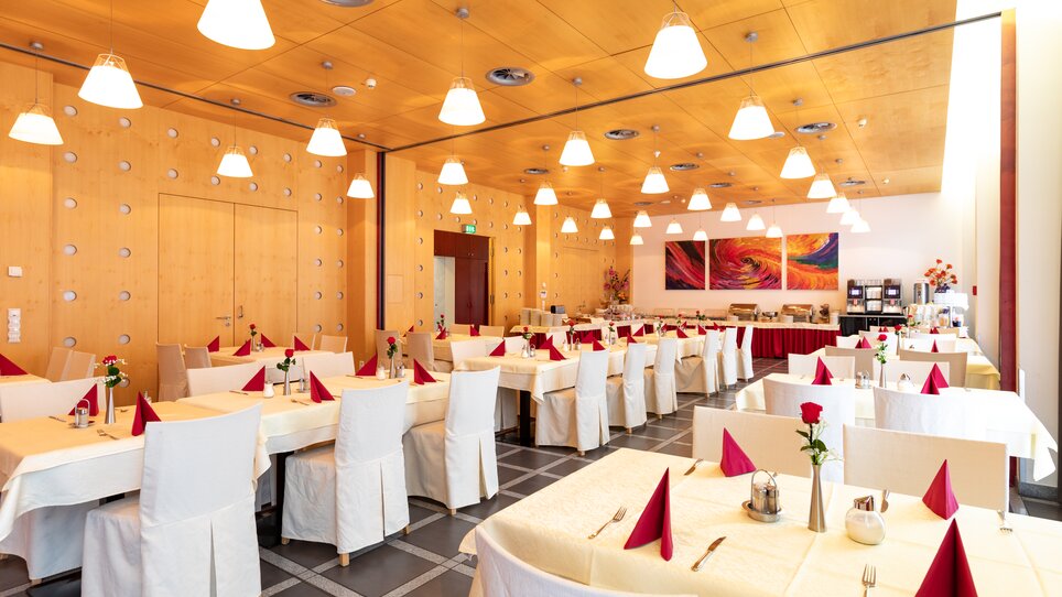 Restaurant with tables and chairs, decorated with red napkins and roses. | © Harry Schiffer