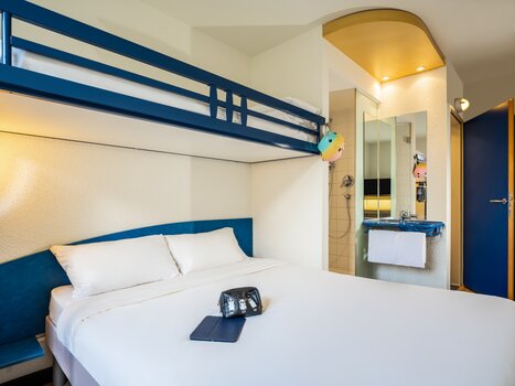 Accogliente camera d'albergo con letto matrimoniale e letto rialzato. | © Ibis Budget