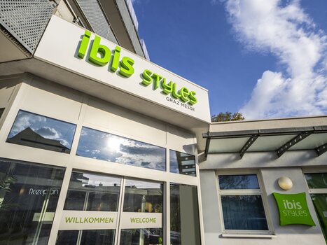 Eingang zum Ibis Styles Graz Messe mit Willkommensschildern. | © Hotel Ibis Styles Graz Messe