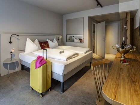 Una camera d'hotel elegante con letto matrimoniale e valigia. | © Hotel Ibis Styles Graz Messe