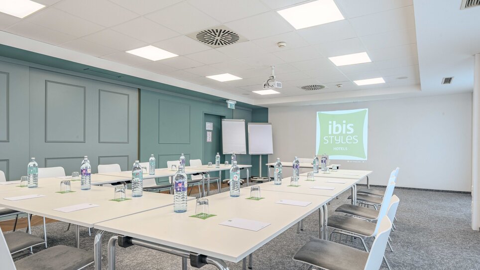 Konferenzraum mit Tischen, Stühlen und Wasserflaschen im Hotel Ibis Styles. | © Katharina Haag