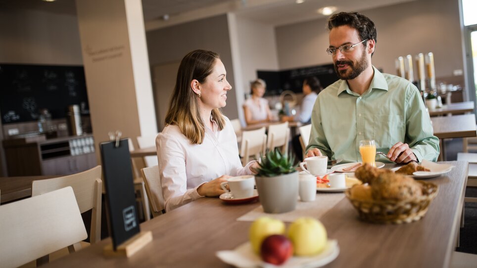 Zwei Personen beim Frühstück in einem hellen Restaurant. | © Jufa Hotels