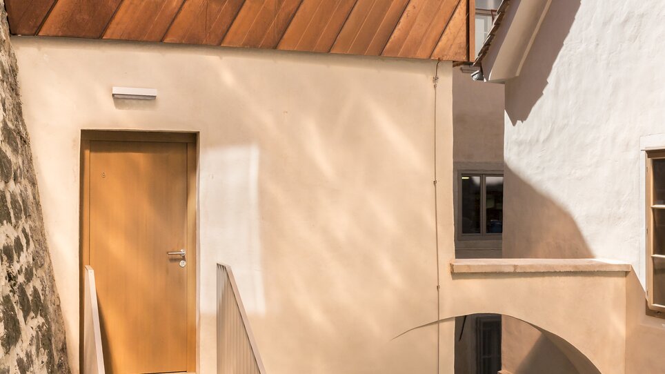 Treppenaufgang zu einem Gebäude mit Holzelementen und Putz. | © KAI 36