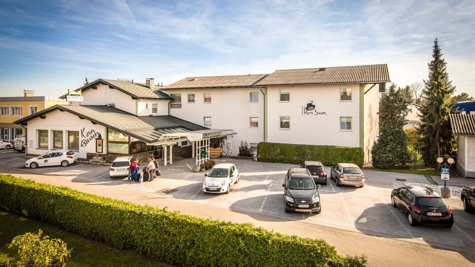 Außenansicht des Hotels Kern Buam mit Parkplatz und Gästen. | © Hotel Kern Buam