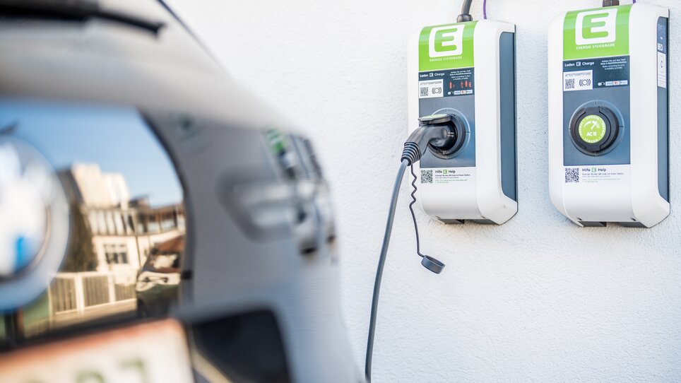 Zwei E-Ladestationen an einer Wand, Kabel verbunden mit einem Elektroauto. | © Mario Gimpl