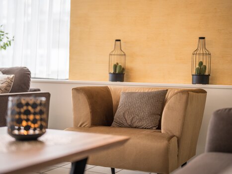 Un'area living elegante con una poltrona beige e piante. | © Mario Gimpl