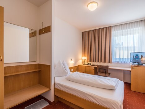 Camera singola moderna con scrivania e televisore. | © Mario Gimpl