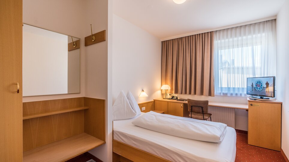 Modernes Einzelzimmer mit Schreibtisch und Fernseher. | © Mario Gimpl