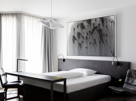 A stylish double room with minimalist decor, a large bed, and a desk. | © Lendhotel