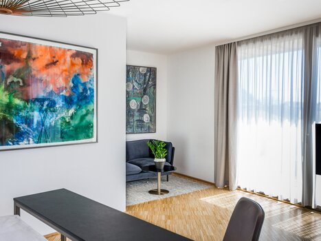 Modern room with artwork, cozy seating area, and large windows. | © Lendhotel