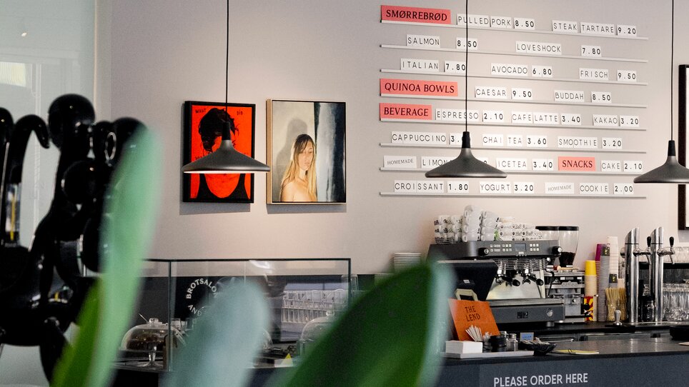 Un caffè moderno con opere d'arte e uno snack bar. | © Lendhotel