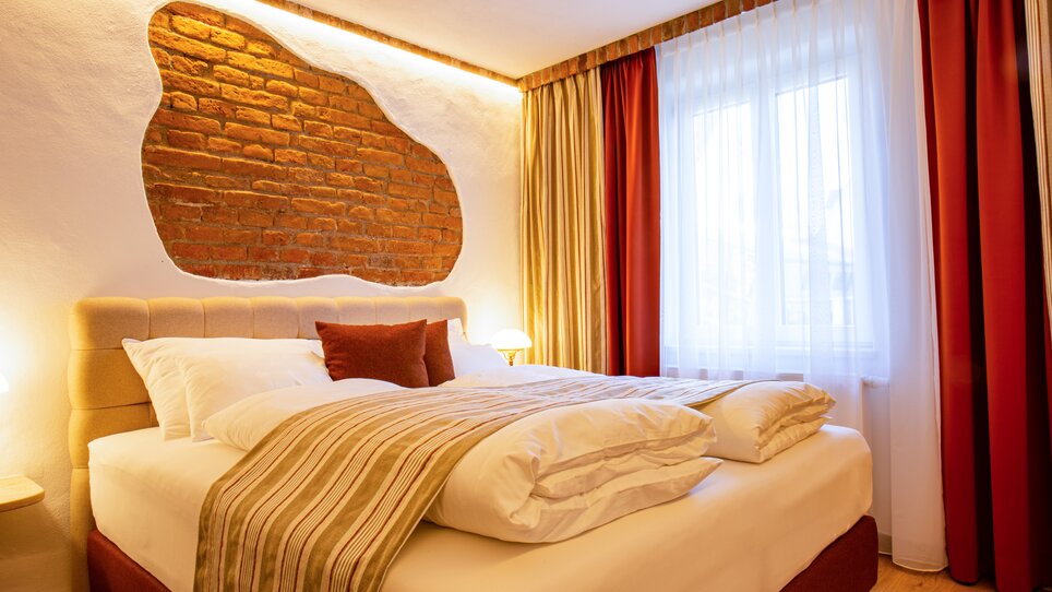 Ein Schlafzimmer mit einem Doppelbett, weißen Kissen und einem Fenster. | © Lendplatzl GmbH