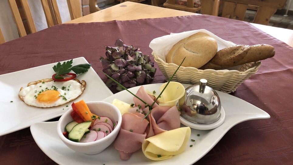 Ein Frühstücksteller mit Ei, Gemüse und Brötchen auf einem Tisch. | © Lendplatzl GmbH