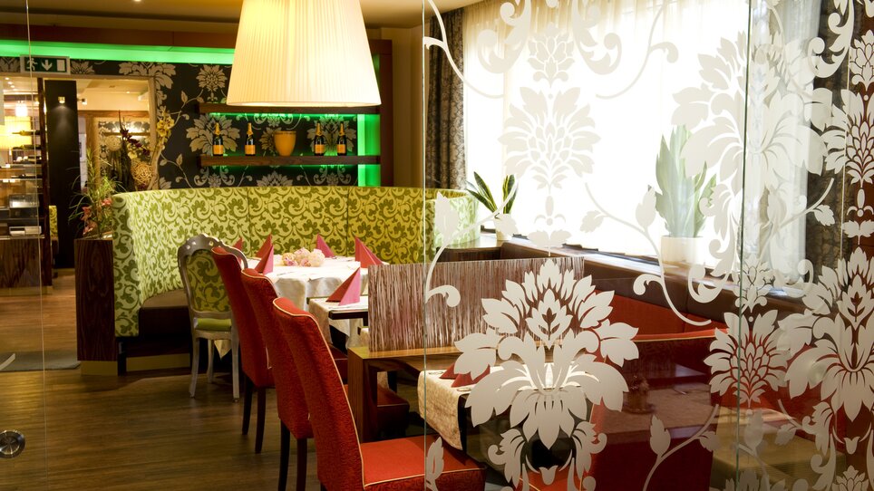Elegant restaurant with green upholstery and red chairs. | © Lindenwirt