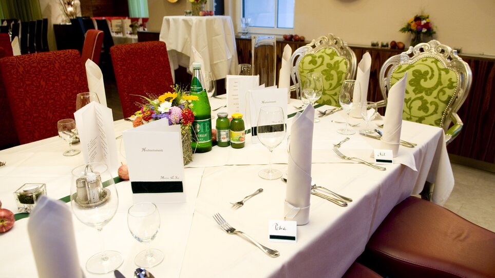 A beautifully arranged table with flowers, drinks, and menus. | © Lindenwirt