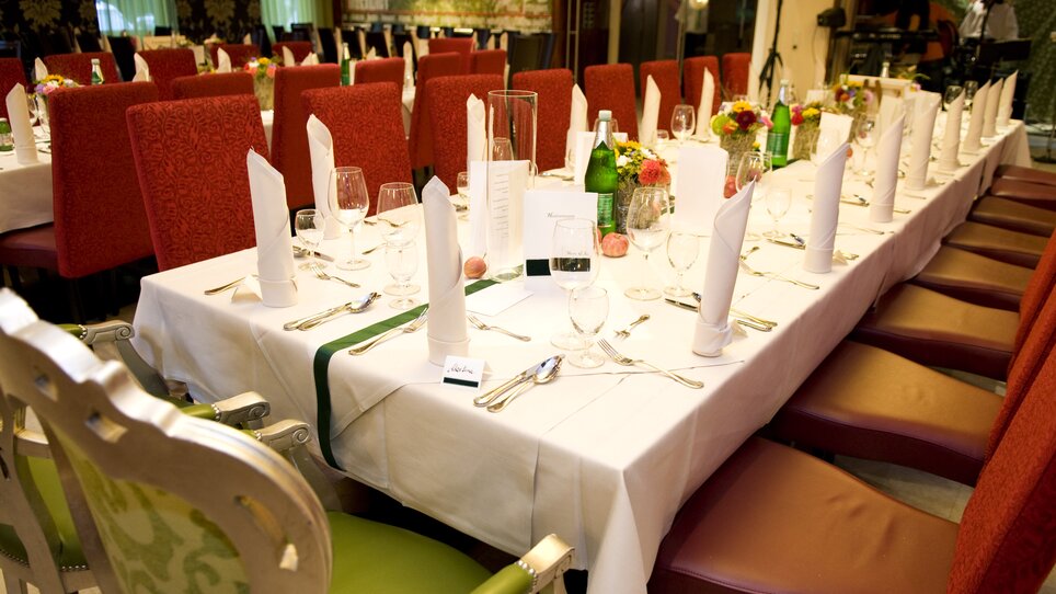 A festively set table with glasses, cutlery, and flowers in an elegant restaurant. | © Lindenwirt