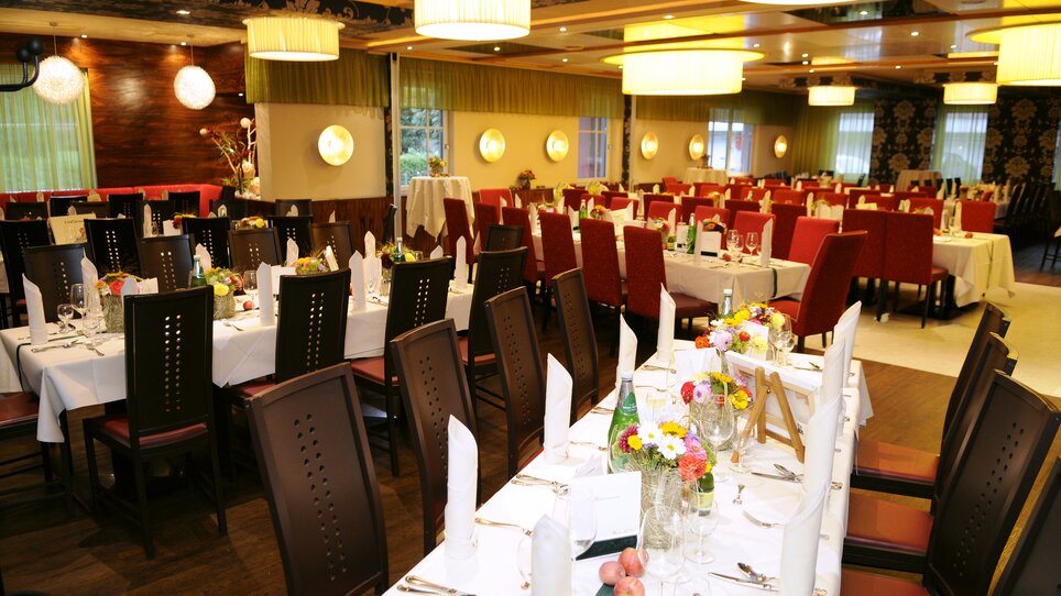 Elegant restaurant featuring red and black chairs with set tables. | © Lindenwirt