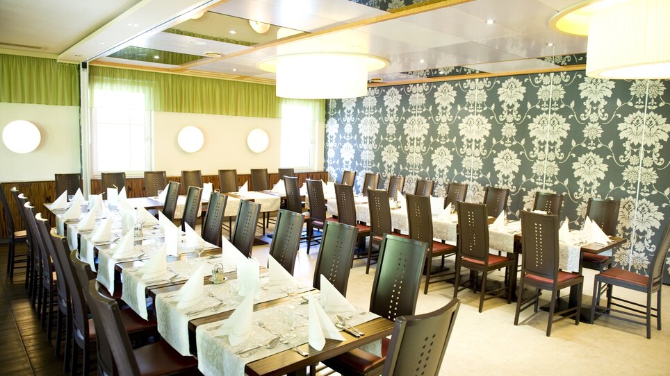 Elegant restaurant setup with set tables and decorative wall design. | © Lindenwirt