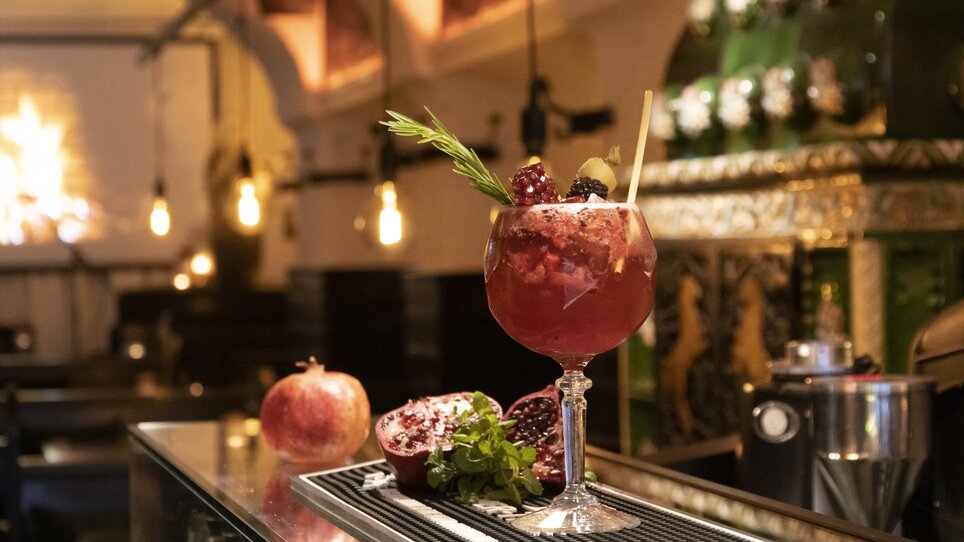 A cocktail on a bar counter, adorned with pomegranate and mint. | © Magdalena Bereźnicka