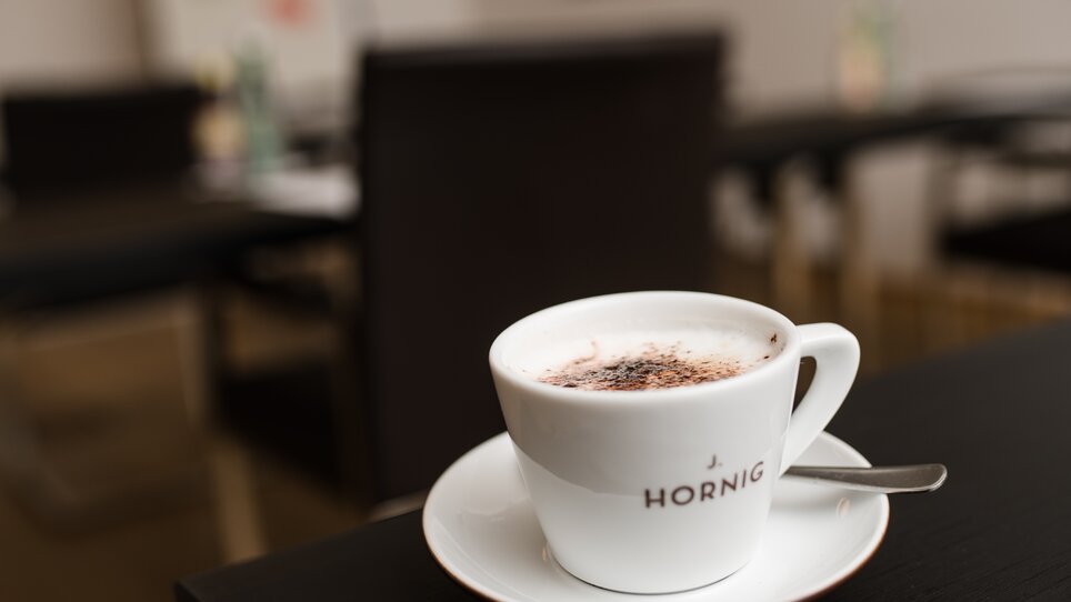 A coffee cup on a table with a spoon beside it. | © Ulf Thausing